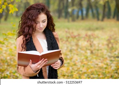 Young Teen Girl Reading A Book In A Park In Autumn