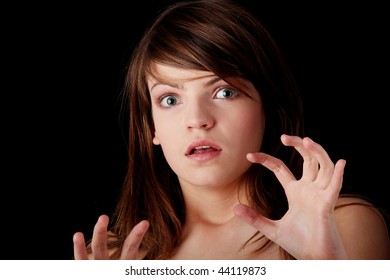 Young teen woman in act to defend herself from somebody striking out at her, isolated on black background