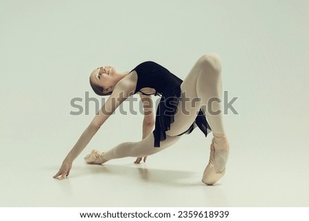 a young teenage ballerina poses in a photo studio sitting in a lunge and bending backwards