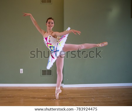 Young teenage ballet dancer wearing a brightly decorated tutu practices in a dance studio