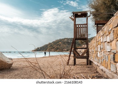 Young teenage boy and girl playing at the foreshore on a desolate beach in front of town in southern Italy, lifeguard tower on the foreground