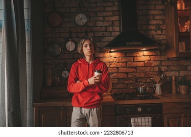 Young teenage boy with long hair in morning routine and preparing on kitchen at home. Stylish zoomer gen Z in casual clothing celebrates new year lights holidays garlands eve xmas enjoying cooking - Shutterstock ID 2232806713