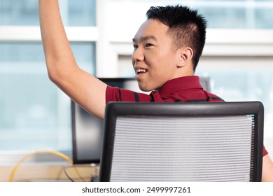 A young teenage college student is raising his hand and asking a question in a computer lab classroom - Powered by Shutterstock