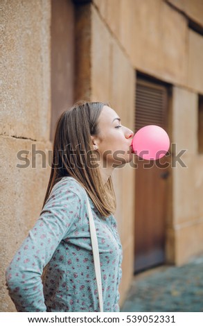 Young teenage girl blowing pink bubble gum