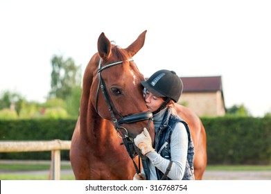 Junge jugendliche Reiter küssen ihr Kastanienpferd. Mehrfarbiges Außenbild mit horizontalem Hintergrund.