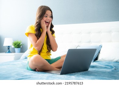 Young Teenage Girl, Little Student Studying Virtual Course, Learning Distance Class Taking Web Training, Looking At Laptop Computer On Bed At Home. Expressive Emotional Excited Teen Girl.