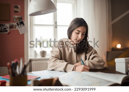 Young teenage girl studying in her room.