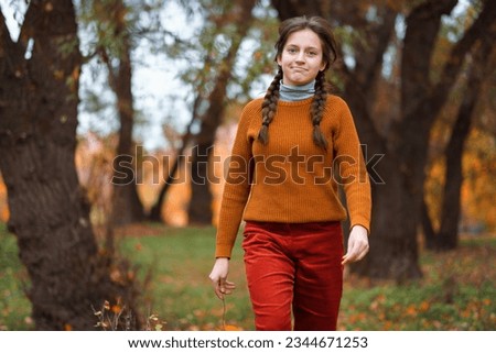 a young teenage girl walks through the autumn forest, walks through a glade and enjoys the beautiful nature and bright yellow leaves