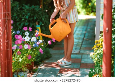 A young teenage girl is watering a vegetable garden with a watering can - Powered by Shutterstock