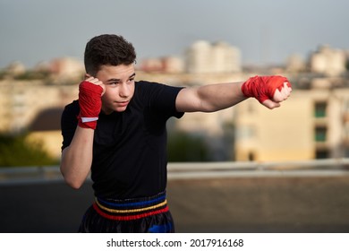 Young teenage kickboxer fighter training on the roof with buildings in background, urban warrior - Powered by Shutterstock