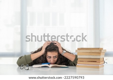 Young teenage school or college university student girl with curly hair have a headache and is tired after hours of reading books and study for the education exam. Anxiety and sore eyes concept.