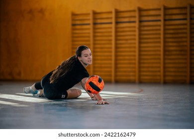 A young teenage sportswoman in action digging a ball on volleyball court on her training. A professional female teenage volleyball player is digging and ball and practicing on her training on court. - Powered by Shutterstock