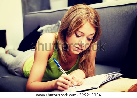 Young teenage woman learning to exam on a sofa.