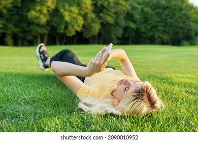 Young teenage woman lying on green grass using smartphone - Powered by Shutterstock