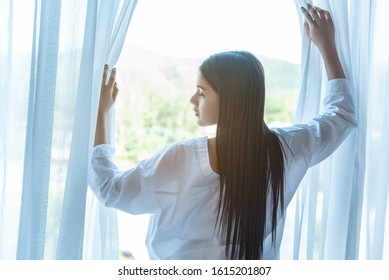 young teenage woman standing side window and look skyscrapers out the window in the morning.relex time and enjoy the view from window.