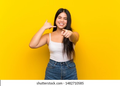 Young teenager Asian girl over isolated yellow background making phone gesture and pointing front - Shutterstock ID 1482710585