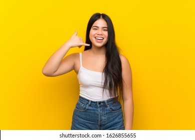 Young teenager Asian girl over isolated yellow background making phone gesture. Call me back sign - Shutterstock ID 1626855655