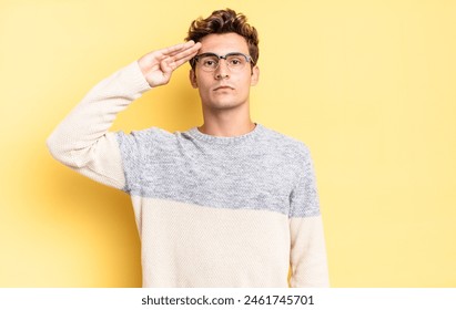 young teenager boy greeting the camera with a military salute in an act of honor and patriotism, showing respect - Powered by Shutterstock