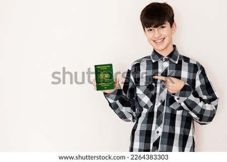 Young teenager boy holding Turkmenistan passport looking positive and happy standing and smiling with a confident smile against white background.
