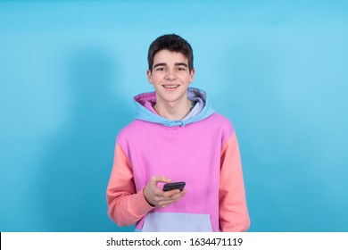 Young Teenager Boy With Mobile Phone Isolated On Blue Background