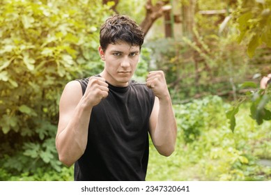 A young teenager boy trains intensively in the fresh air, near the house, boxing with himself, a fight with a shadow, the boy even has a damaged arm, a passion for sports - Powered by Shutterstock