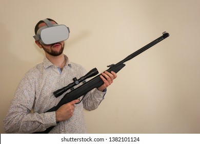 Young Teenager Boy Using A Weapon Like A Sniper In A Virtual Reality Video Game. He Shoots A Gun In Real Life, And Shows The Violence And Aggressive Behavior Of War Games. He Feels Like A Hero.