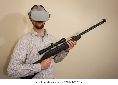 Young Teenager Boy Using A Weapon Like A Sniper In A Virtual Reality Video Game. He Shoots A Gun In Real Life, And Shows The Violence And Aggressive Behavior Of War Games. He Feels Like A Hero.