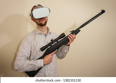 Young Teenager Boy Using A Weapon Like A Sniper In A Virtual Reality Video Game. He Shoots A Gun In Real Life, And Shows The Violence And Aggressive Behavior Of War Games. He Feels Like A Hero.