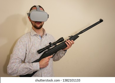 Young Teenager Boy Using A Weapon Like A Sniper In A Virtual Reality Video Game. He Shoots A Gun In Real Life, And Shows The Violence And Aggressive Behavior Of War Games. He Feels Like A Hero.