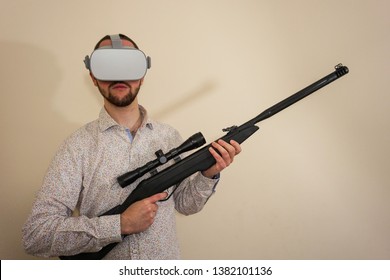 Young Teenager Boy Using A Weapon Like A Sniper In A Virtual Reality Video Game. He Shoots A Gun In Real Life, And Shows The Violence And Aggressive Behavior Of War Games. He Feels Like A Hero.