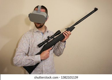 Young Teenager Boy Using A Weapon Like A Sniper In A Virtual Reality Video Game. He Shoots A Gun In Real Life, And Shows The Violence And Aggressive Behavior Of War Games. He Feels Like A Hero.