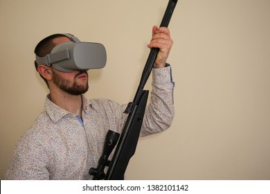 Young Teenager Boy Using A Weapon Like A Sniper In A Virtual Reality Video Game. He Shoots A Gun In Real Life, And Shows The Violence And Aggressive Behavior Of War Games. He Feels Like A Hero.