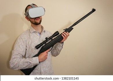 Young Teenager Boy Using A Weapon Like A Sniper In A Virtual Reality Video Game. He Shoots A Gun In Real Life, And Shows The Violence And Aggressive Behavior Of War Games. He Feels Like A Hero.