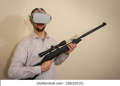 Young Teenager Boy Using A Weapon Like A Sniper In A Virtual Reality Video Game. He Shoots A Gun In Real Life, And Shows The Violence And Aggressive Behavior Of War Games. He Feels Like A Hero.