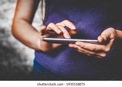young teenager girl hand using mobile phone or smartphone on gray wall background