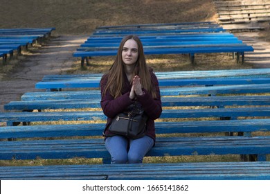 A Young Teenager Girl Sits Alone On A Tribune On An Open-air Park Bench And Claps Her Hands. A Single Spectator Viewer Came To The Street Concert. Bad Concert.