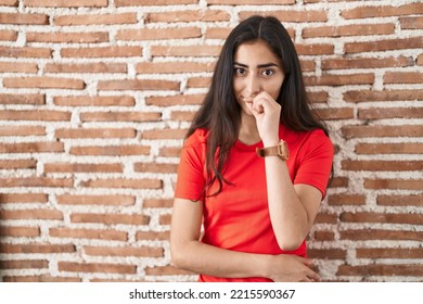 Young Teenager Girl Standing Over Bricks Wall Mouth And Lips Shut As Zip With Fingers. Secret And Silent, Taboo Talking 