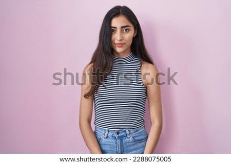 Young teenager girl wearing casual striped t shirt relaxed with serious expression on face. simple and natural looking at the camera. 