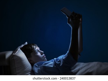 Young teenager guy in bed using tablet pc - Powered by Shutterstock