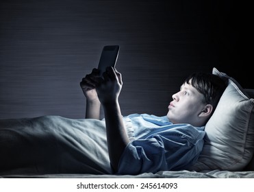 Young teenager guy in bed using tablet pc - Powered by Shutterstock