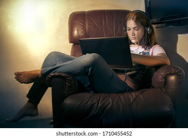 Young Teenager Latin Girl Seated Comfortable On Dark Brown Couch At Home With Laptop Studying Online