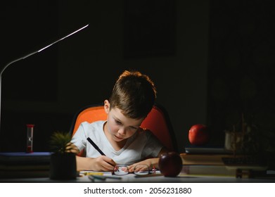 young teenager schoolboy at the table doing homework in the dark room - Powered by Shutterstock