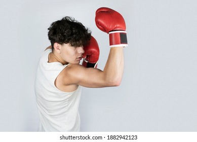 The young teenager is seriously engaged in boxing, trains even at home in boxing gloves, works out a blow from below in a jaw, carries out fight with a shadow - Powered by Shutterstock