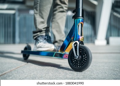 young teenager in sneaker on modern extreme stunt kick scooter in skatepark
