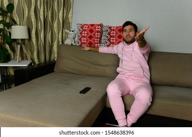 Young Television Addict Man Sitting On Sofa At Home And Watching TV Using Remote Control, Looking Excited, Pumping Out Someone Else's Comedy Comedy Movie Or Live Music At Night