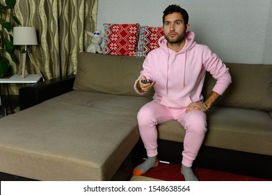 Young Television Addict Man Sitting On Sofa At Home And Watching TV Using Remote Control, Looking Excited, Pumping Out Someone Else's Comedy Comedy Movie Or Live Music At Night