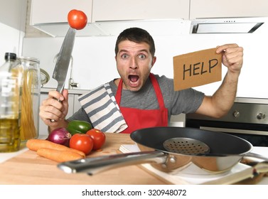 Young Terrified Man At Home Kitchen Wearing Cook Apron Showing Help Sign Looking Desperate In Stress Holding Knife With Tomato In Domestic Mess Cooking Concept