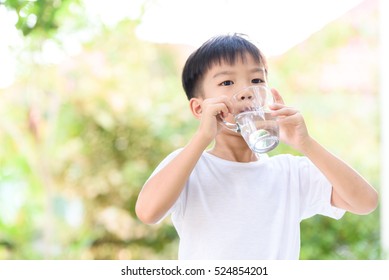 Young Thai Boy Drinking Water From Glass In The Garden