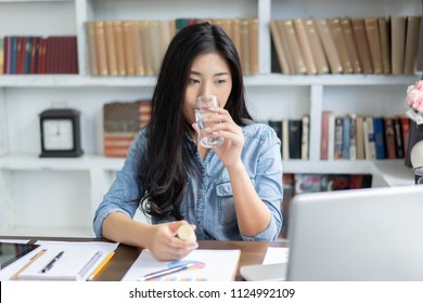 Young Thai Girl Business Woman Taking Medicine And Drinking Water,holding Pills ,glass Of Water At Workplace,she Working Hard With Laptop While Feels Sick,medicine,health Care Medical People Concept