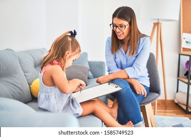 Young therapist woman speaking and treating child, counselor and behaviour correction at pedagogue payroom taking notes on clipboard